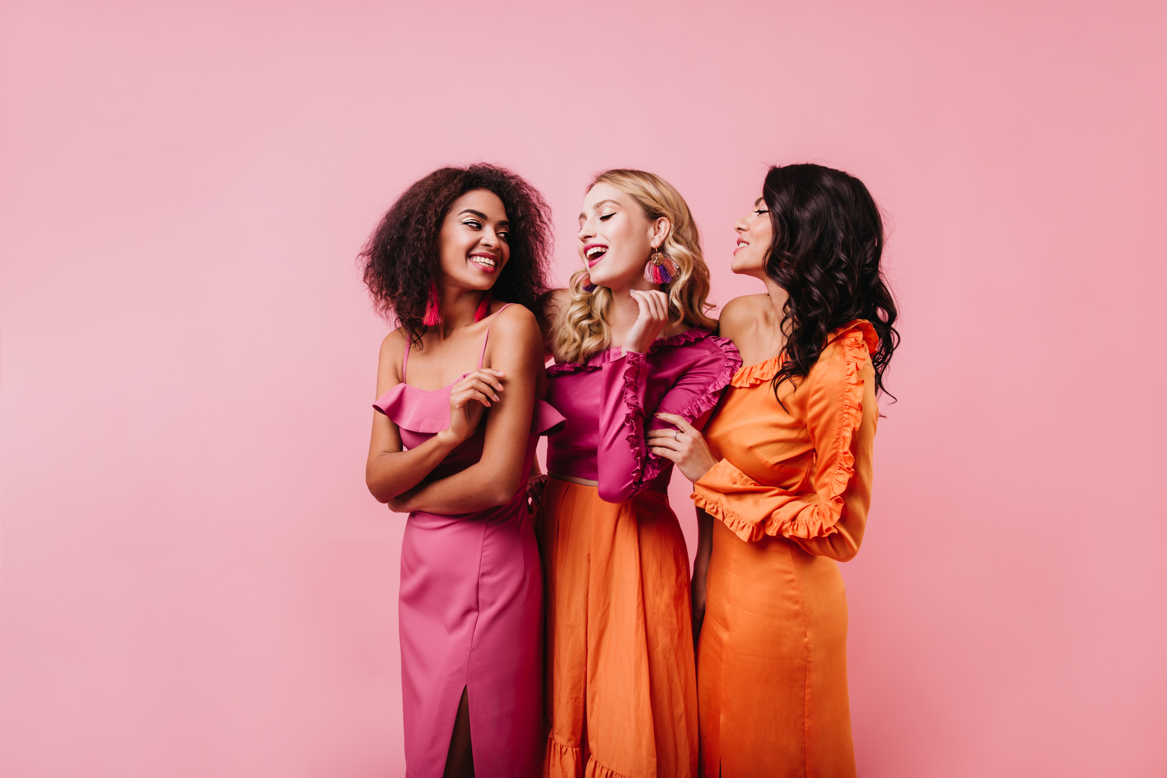 Three Girls Dancing on Pink Background. Studio Shot of Female Friends Chilling Together